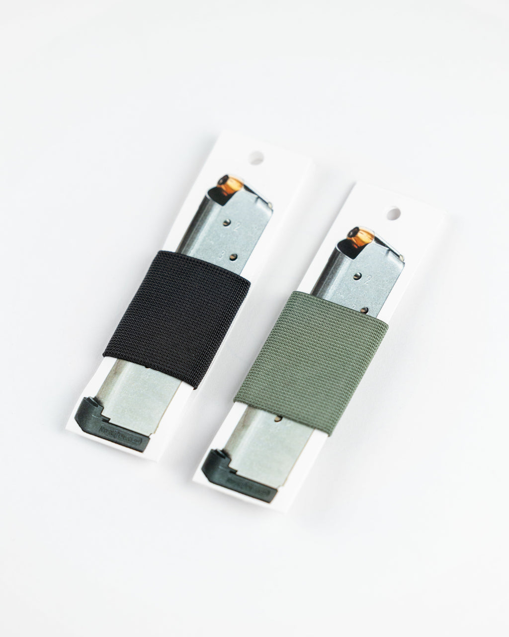 Two pistol magazines, each wrapped with SLIM carry in black and olive green
