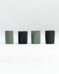 Four SLIM carry accessories arranged in a row on a light gray studio background, alternating between muted sage green and black.