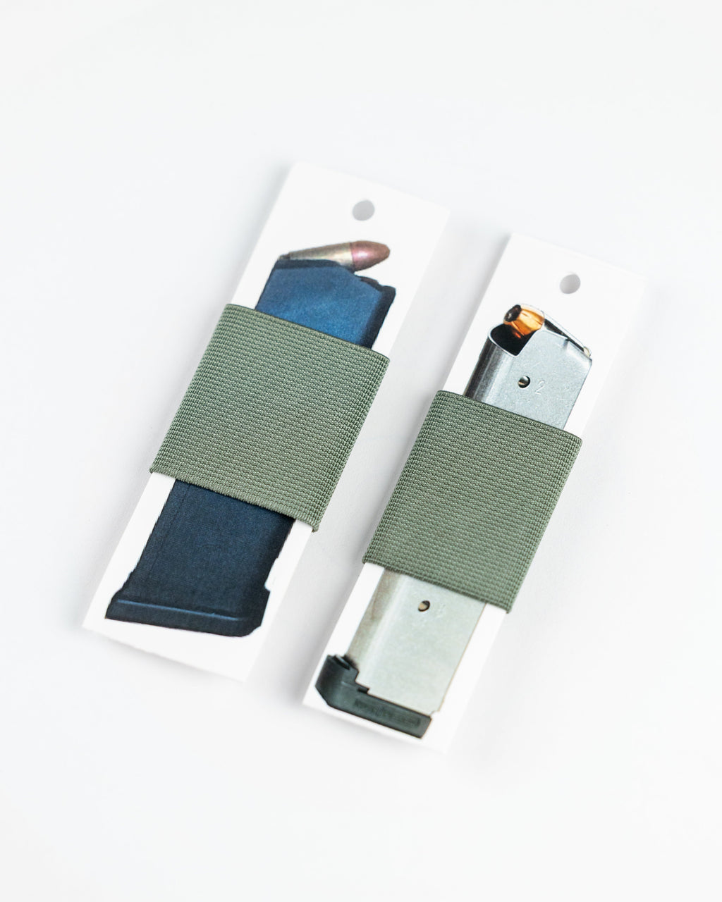 Two olive green elastic gun belt wraps holding magazines on white display cards, photographed on a clean white background.